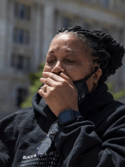 Rhanda Dormeus is a Black woman and is Korryn Gaines mother. She is standing outside and has her hand over her mouth and eyes closed.  AP photo credit Amanda Andrade-Rhoades.