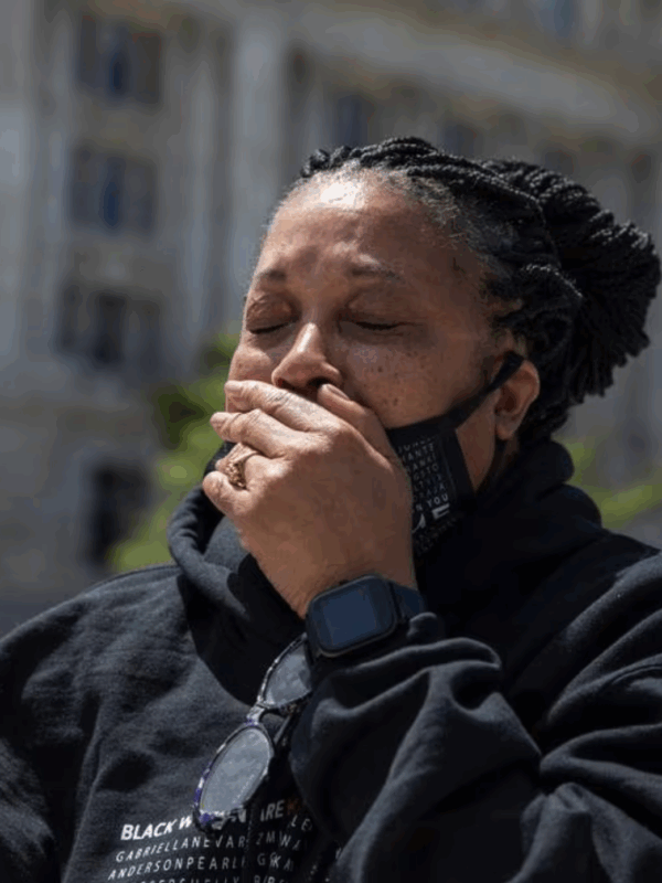 Rhanda Dormeus is a Black woman and is Korryn Gaines mother. She is standing outside and has her hand over her mouth and eyes closed.  AP photo credit Amanda Andrade-Rhoades.