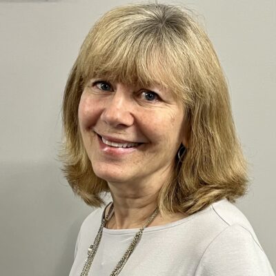 Val is a blonde woman seen smiling, wearing a necklace