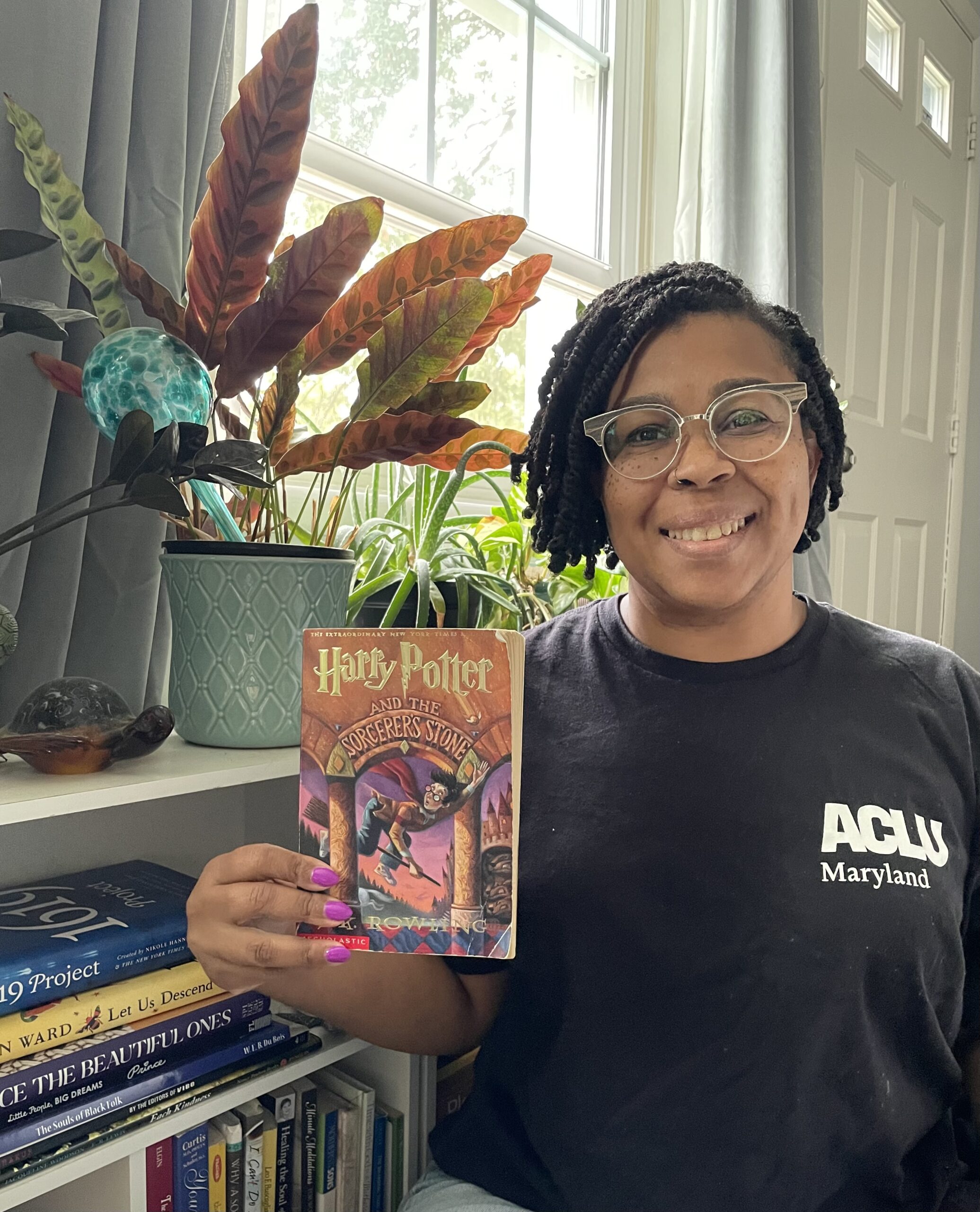 Stefany holds Harry Potter and the Sorcerer Stone in a black ACLU Maryland shirt