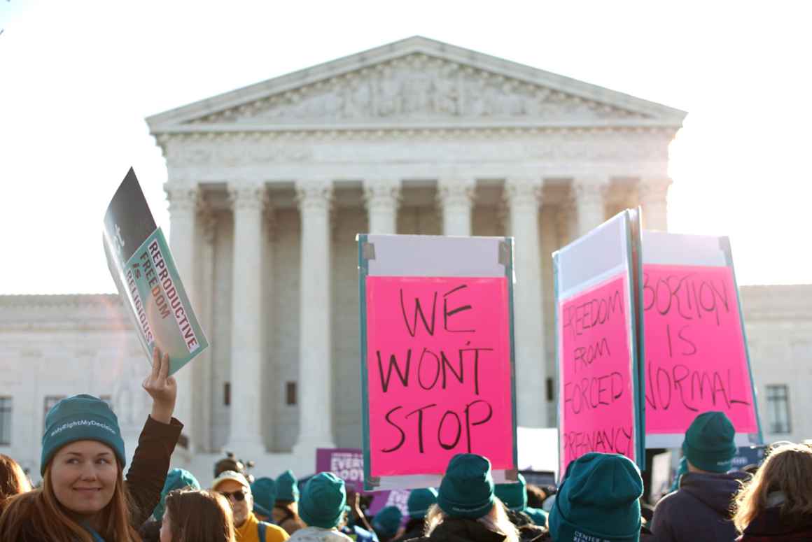 At an abortion rights rally in front of the Supreme Court, people hold signs that say We Won't Stop.