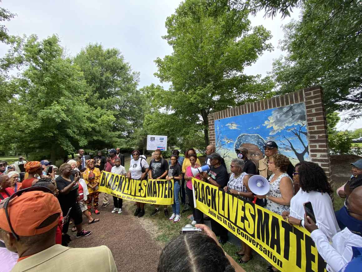2021 Freedom Riders hold a Black Lives Matter banner in front of a mural at the Harriet Tubman museum.