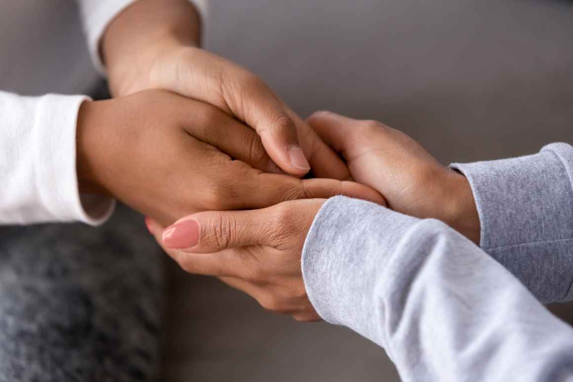 An adult is holding the hands of a child.