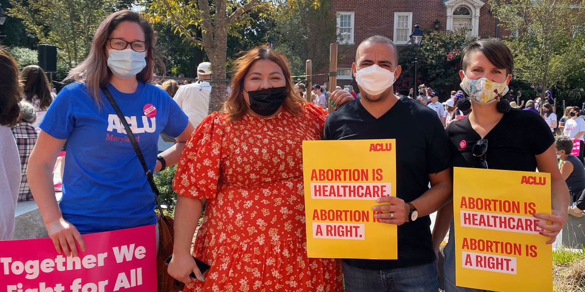 Ellen Hutton, Lorena Diaz, Sergio España, and Amy Cruice are at a rally in Annapolis for abortion rights. They hold protest signs and are standing together looking at the camera.