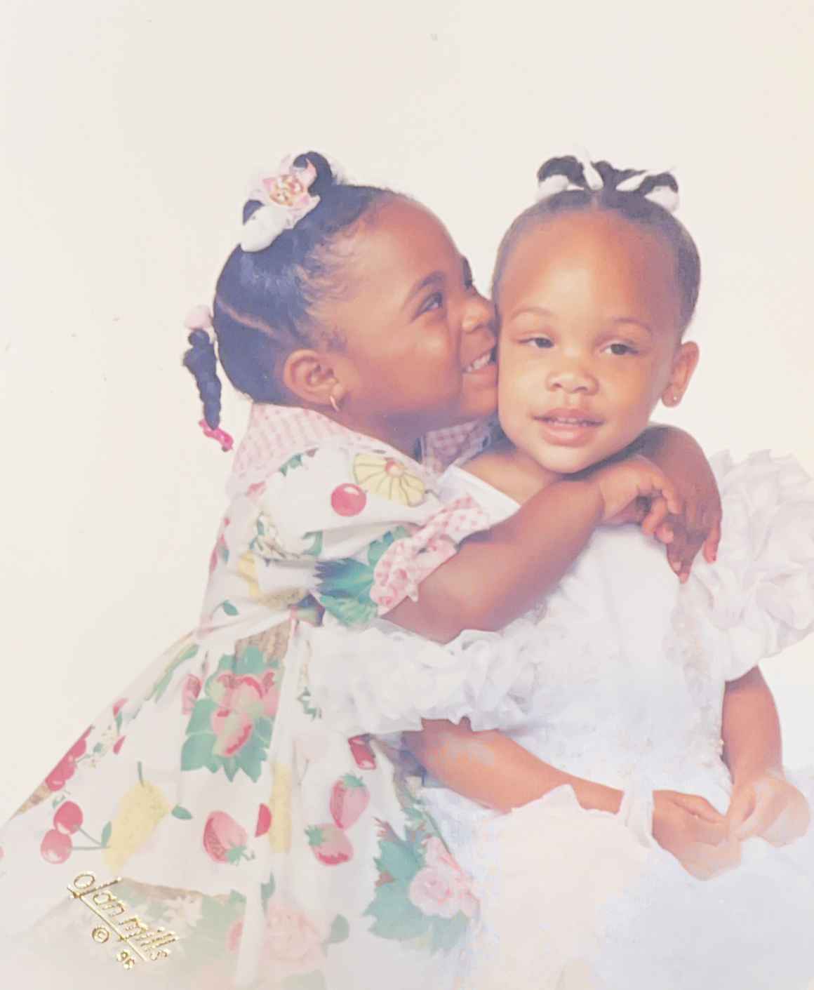 Antoinette and Alicia are sisters. They are young children in this photo of them hugging.They were at a very 90’s Olan Mills photoshoot.