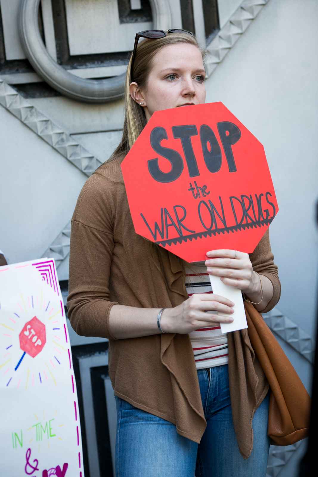 A white person is holding a sign that says "Stop the war on drugs."