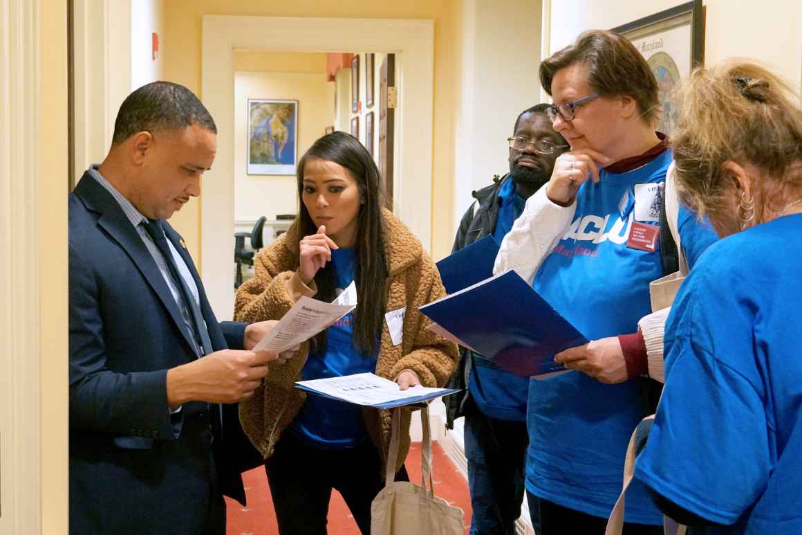 ACLU of Maryland members are talking with Senator Antonio Hayes at the Lobby Day 2020 event in Annapolis wearing blue ACLU t-shirts.