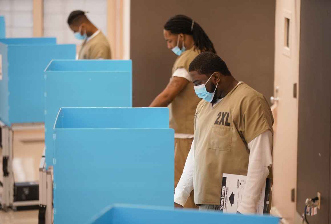 Picture shows a few Black people who are incarcerated wearing surgical masks voting.