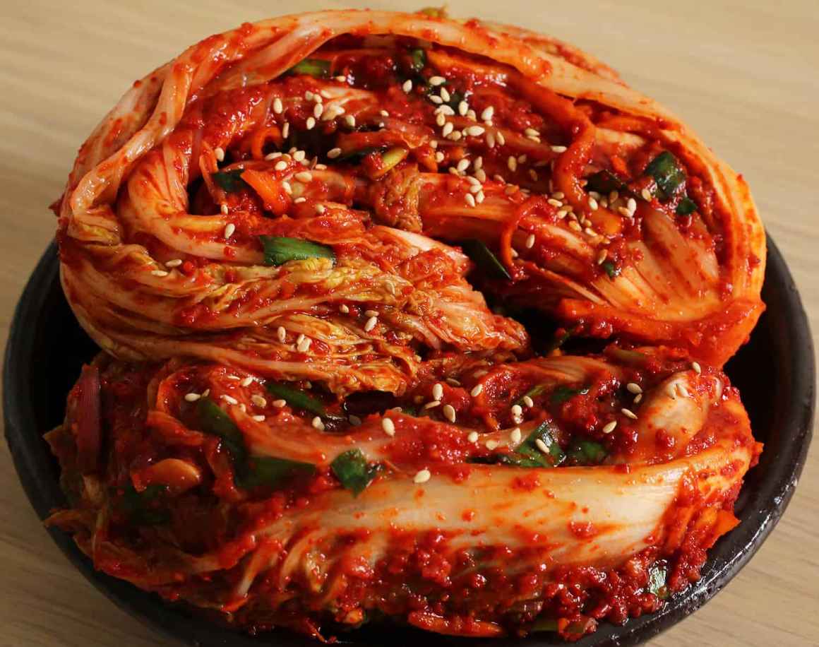 Plate with a whole cabbage kimchi plated with sesame seeds sprinkled on top. Photo from the Maangchi website.