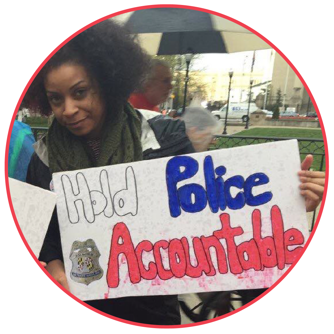 Black woman holding a protest sign that says, "Hold police accountable."
