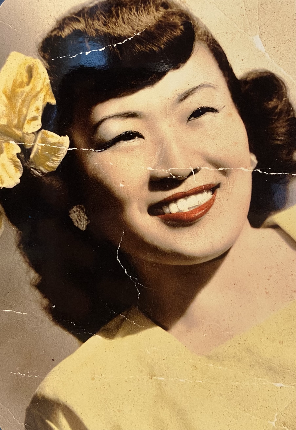 Olivia Spaccasi's grandmother when she was still living in Hawaii. She is Korean and has a yellow flower in her hair.