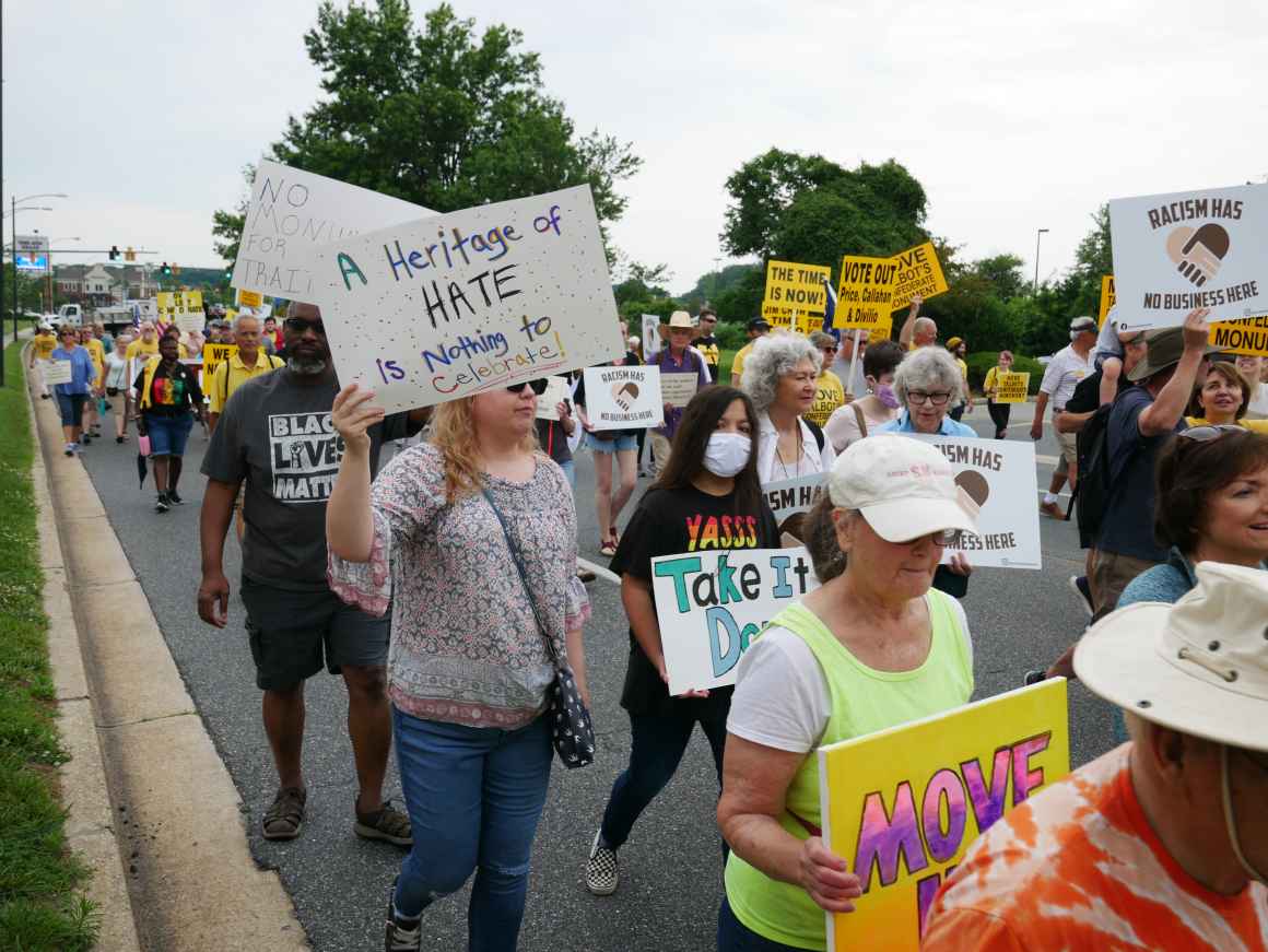 People marching at the Move the Monument rally in Talbot County on Juneteenth. A white person is holding a sign that says "A heritage of hate is nothing to celebrate."