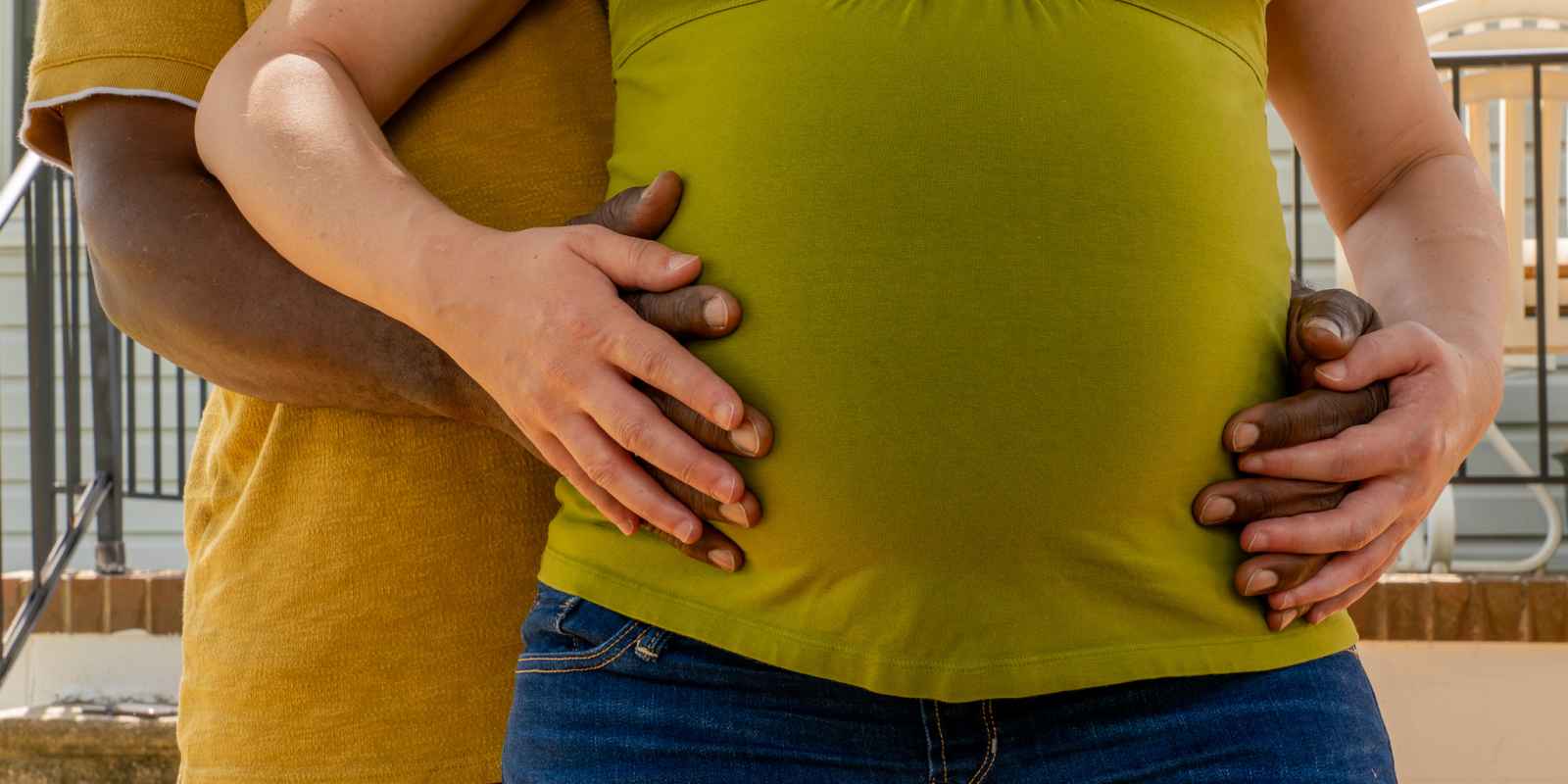 Gordon Pack has his hands around his wife's pregnant belly.