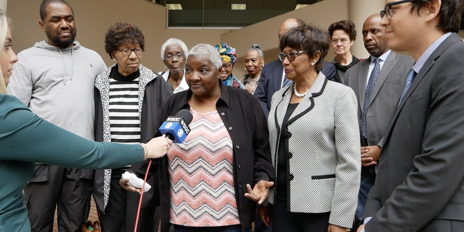 Local Black activists, residents, and Maryland laywers are in a group outside of a Federalsburg courthouse with a reporter holding a microphone up to a Black resident.