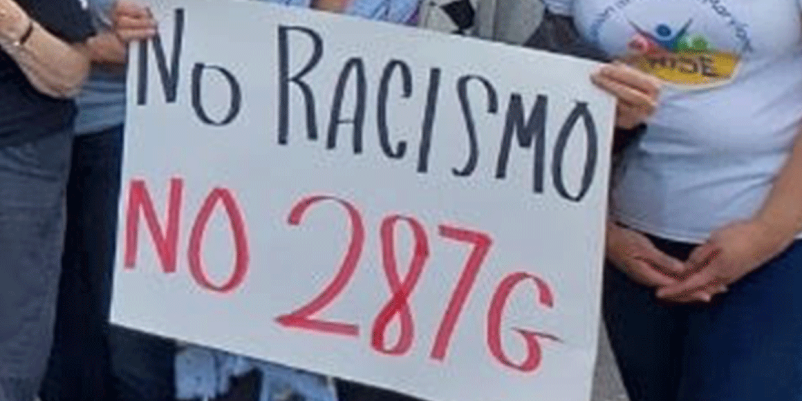People hands shown holding a protest sign that says, "No Racismo, no 287g."