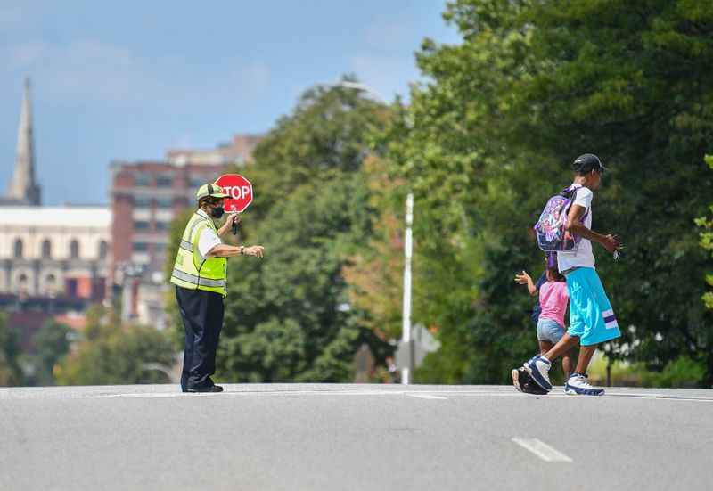 A crossing guard is guiding two students across a street.