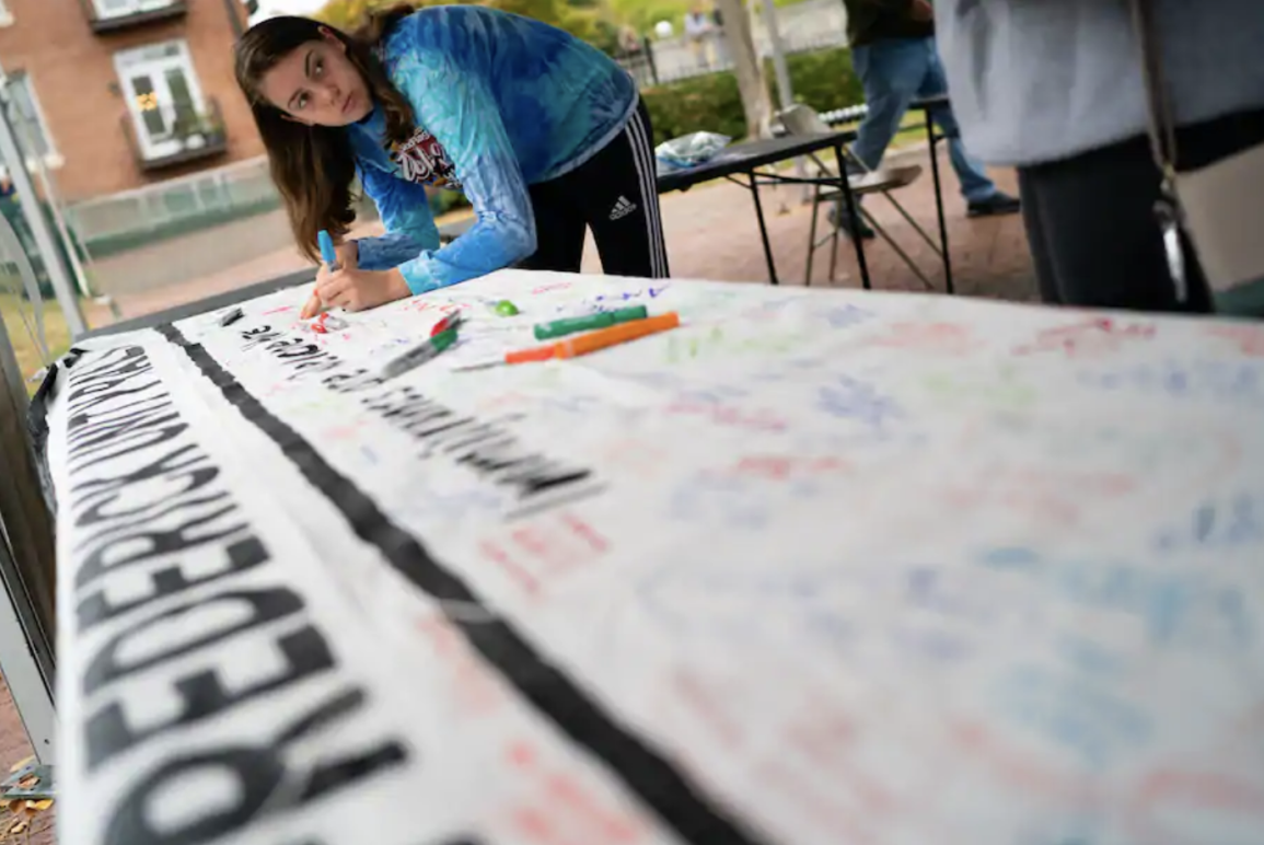 A woman signs a banner at a rally in support of immigrants in Frederick in 2019. (Sarah L. Voisin/The Washington Post)