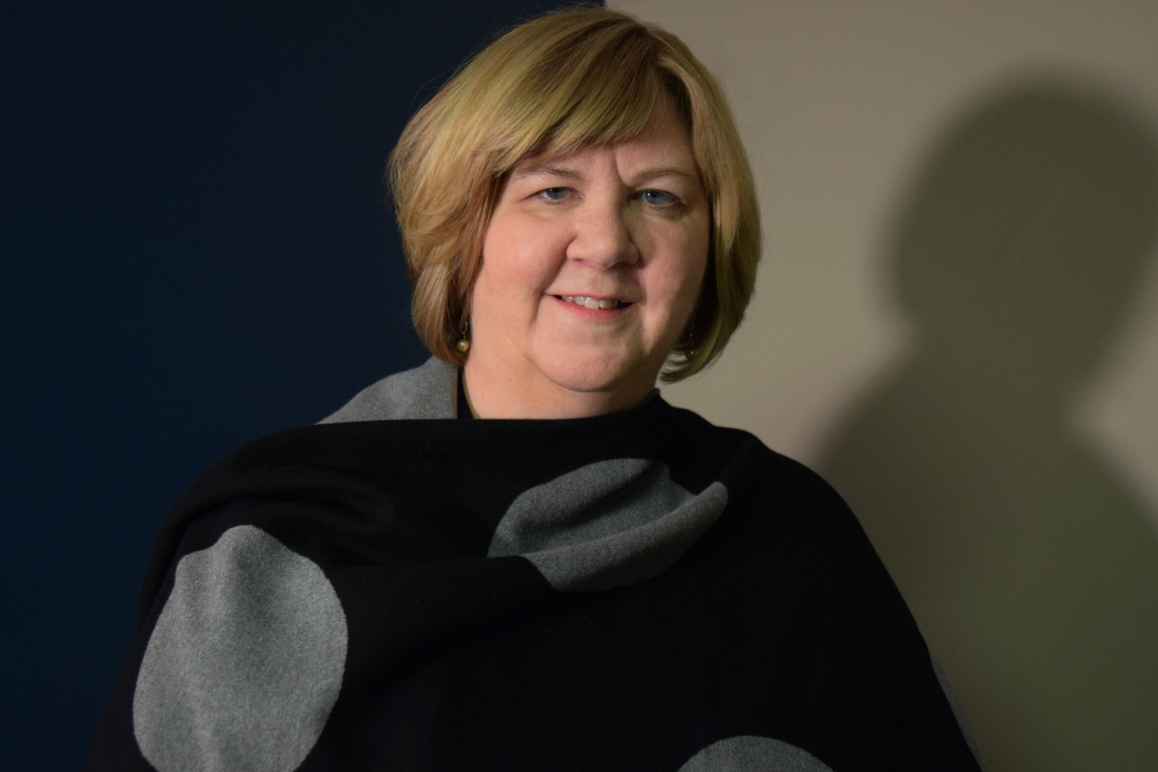Laura Howell, white woman with blond hair, wearing a black and gray wrap.