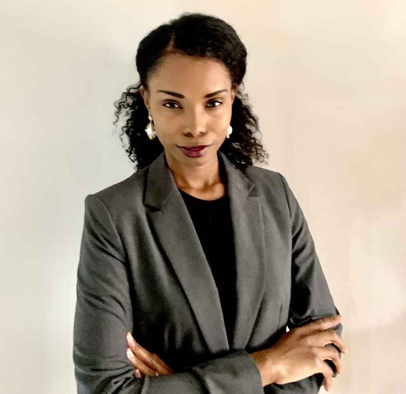 Picture of Tierney Peprah, a Black woman, with her hair partially pulled back and wearing a gray suit and a black shirt.