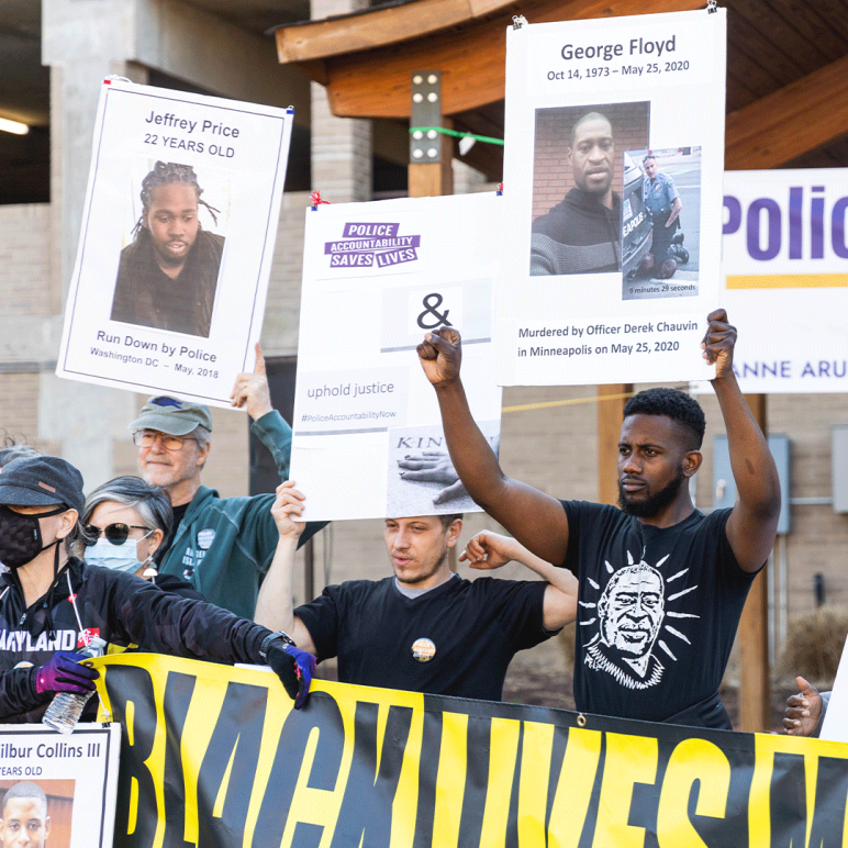 Protesters at a police accountability rall holding up signs with photos of Black people killed by police.