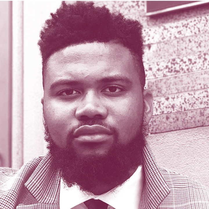 Nehemiah Bester is a Black man with short hair and a beard, and is wearing a sport jacket, collared shirt, and tie. Image has a burgundy and white gradient map color profile.