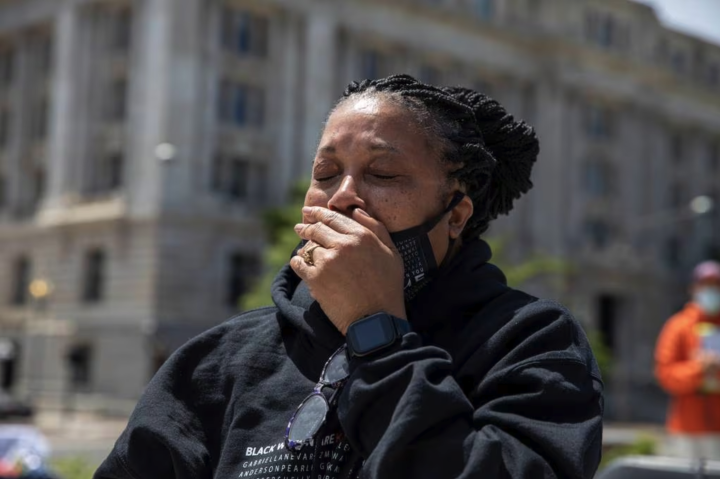 Rhanda Dormeus is a Black woman and is Korryn Gaines mother. She is standing outside and has her hand over her mouth and eyes closed.  AP photo credit Amanda Andrade-Rhoades.
